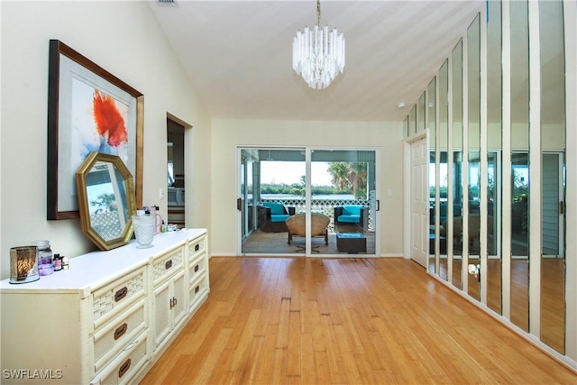 hallway featuring vaulted ceiling, an inviting chandelier, and light hardwood / wood-style floors