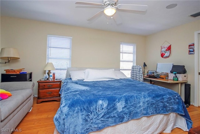 bedroom featuring ceiling fan, light hardwood / wood-style floors, and multiple windows