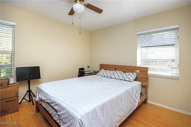 bedroom with ceiling fan, light hardwood / wood-style floors, and multiple windows