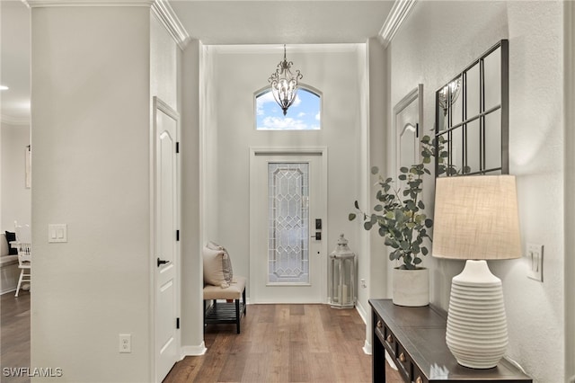 foyer featuring an inviting chandelier, ornamental molding, and dark wood-type flooring