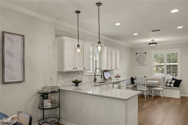 kitchen with kitchen peninsula, hanging light fixtures, decorative backsplash, white cabinetry, and sink