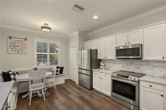 kitchen featuring white cabinets, stainless steel appliances, tasteful backsplash, and dark wood-type flooring