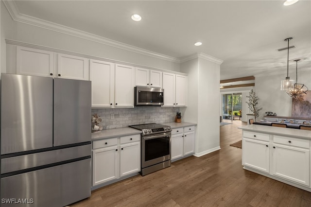 kitchen featuring appliances with stainless steel finishes, pendant lighting, white cabinets, and tasteful backsplash