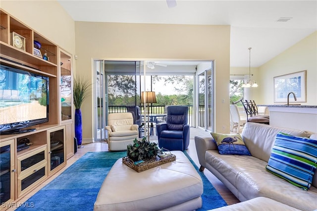 living room featuring lofted ceiling and ceiling fan with notable chandelier