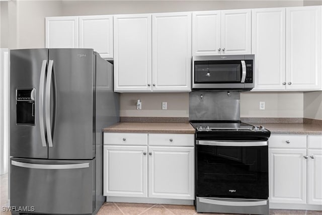 kitchen with light tile patterned flooring, white cabinets, and appliances with stainless steel finishes