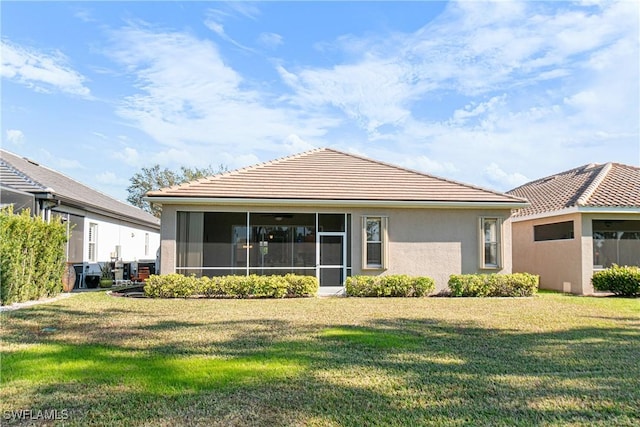 rear view of property featuring a sunroom and a lawn