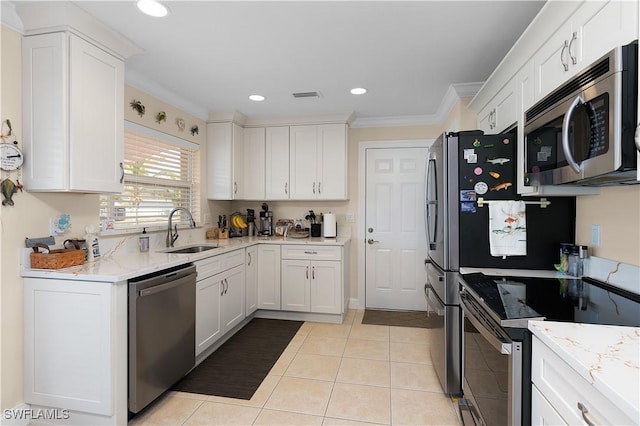 kitchen with appliances with stainless steel finishes, crown molding, sink, light tile patterned floors, and white cabinetry