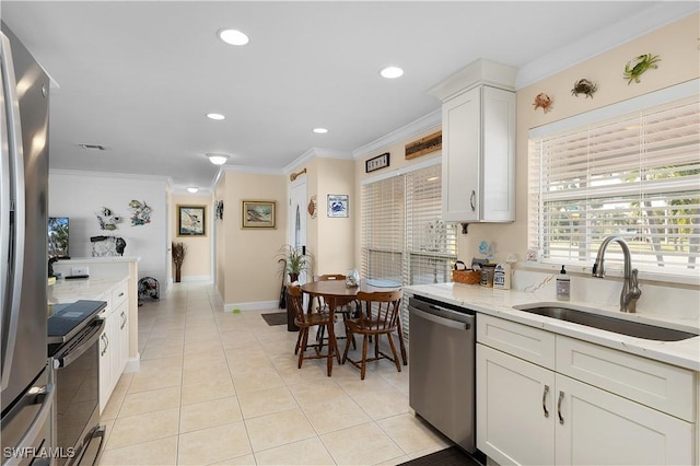 kitchen featuring appliances with stainless steel finishes, light stone counters, sink, light tile patterned floors, and white cabinetry