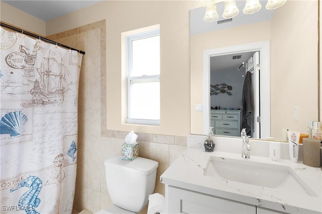 bathroom with a shower with curtain, vanity, toilet, and tile walls