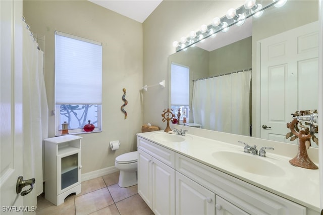 bathroom featuring toilet, tile patterned flooring, double vanity, and a sink