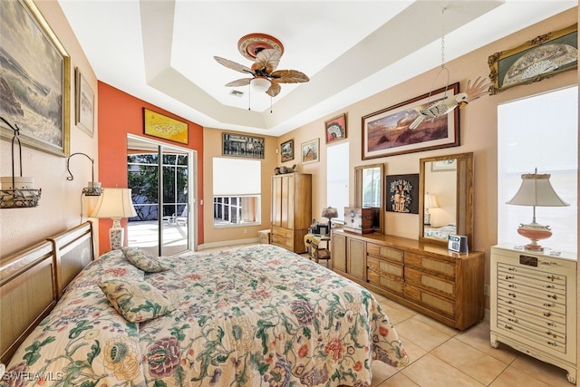 bedroom featuring access to exterior, a raised ceiling, ceiling fan, and light tile patterned floors