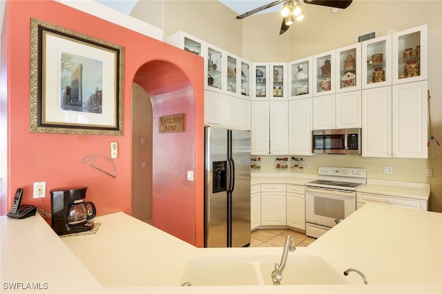 kitchen featuring light tile patterned floors, visible vents, white cabinets, appliances with stainless steel finishes, and glass insert cabinets