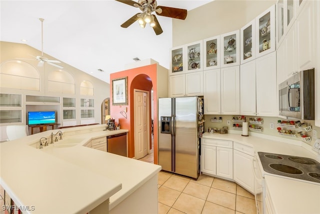 kitchen featuring arched walkways, a ceiling fan, vaulted ceiling, stainless steel appliances, and a sink