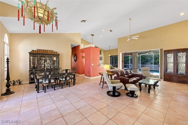 interior space featuring light tile patterned floors, visible vents, a ceiling fan, high vaulted ceiling, and baseboards