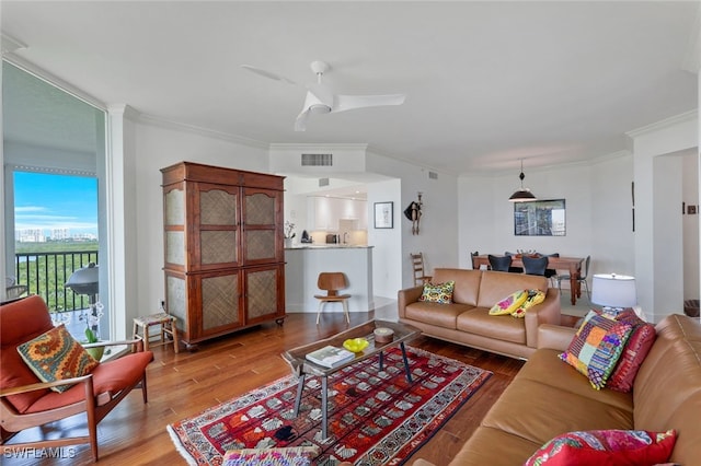 living room with hardwood / wood-style flooring, ceiling fan, and crown molding