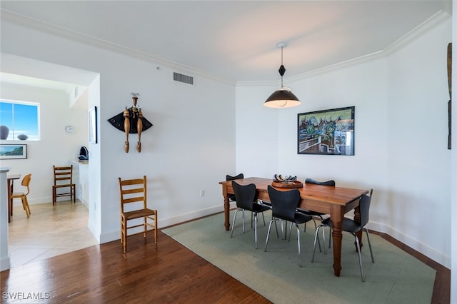 dining area with wood-type flooring and ornamental molding