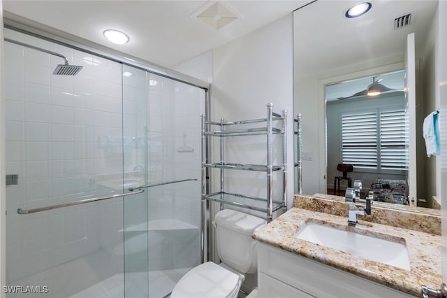 bathroom featuring vanity, toilet, ceiling fan, and a shower with shower door