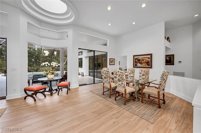 dining room with light hardwood / wood-style floors and a towering ceiling