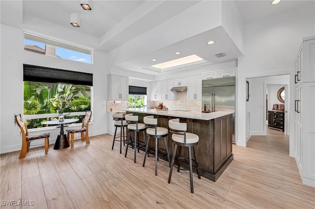 kitchen with a breakfast bar area, white cabinets, a center island, backsplash, and a tray ceiling