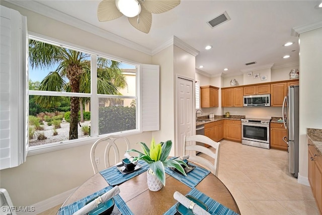 tiled dining space featuring ceiling fan, crown molding, and sink