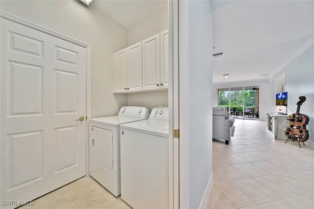 laundry area with washing machine and dryer, light tile patterned flooring, and cabinets