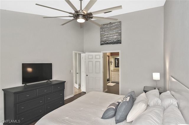 bedroom featuring ceiling fan, dark wood-type flooring, ensuite bathroom, and a towering ceiling