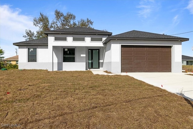 prairie-style house featuring a garage and a front lawn