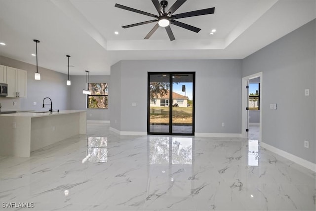 unfurnished living room with plenty of natural light, sink, and a tray ceiling