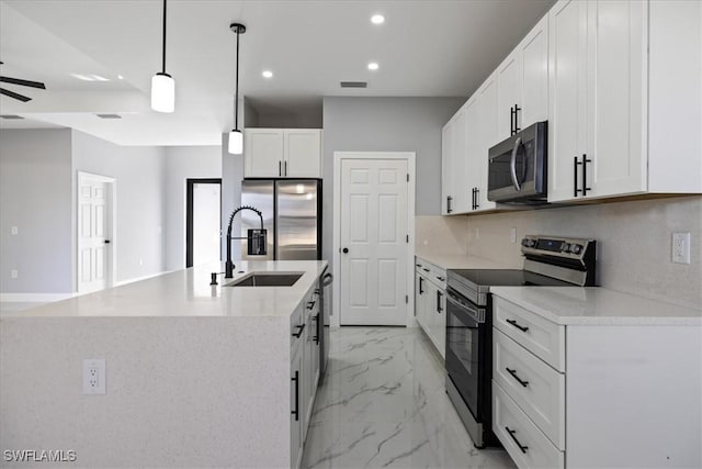 kitchen with white cabinets, decorative light fixtures, stainless steel appliances, an island with sink, and tasteful backsplash