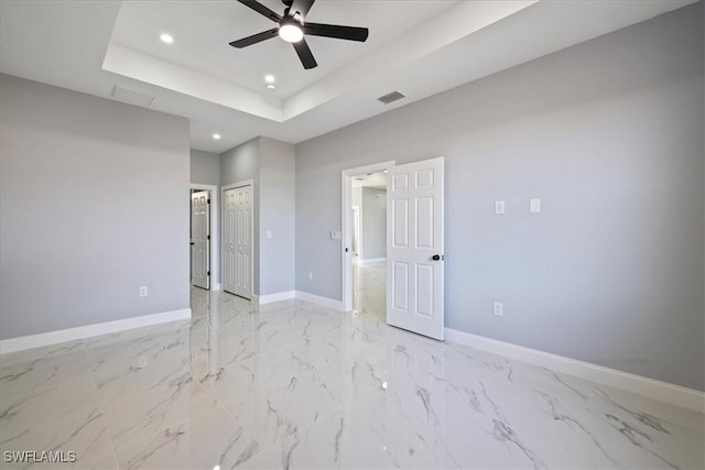 unfurnished bedroom with ceiling fan and a tray ceiling