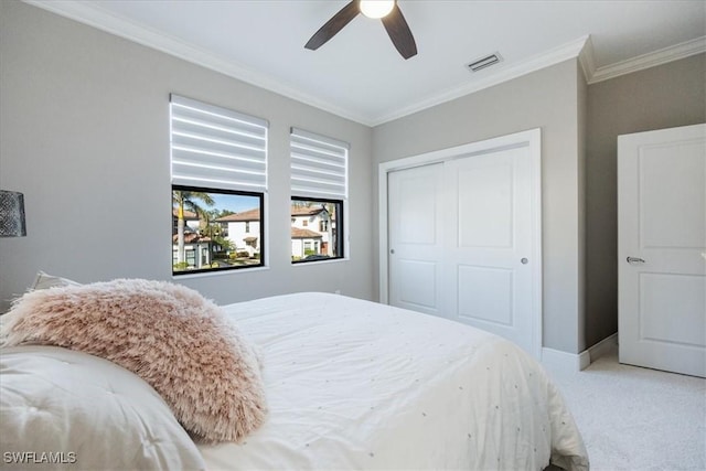 carpeted bedroom with crown molding, ceiling fan, and a closet