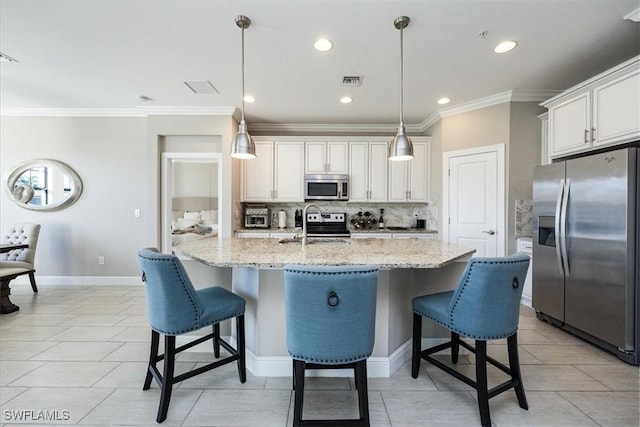 kitchen with decorative light fixtures, white cabinetry, backsplash, a kitchen island with sink, and stainless steel appliances