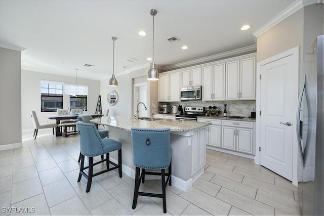 kitchen with sink, white cabinets, hanging light fixtures, a kitchen island with sink, and stainless steel appliances