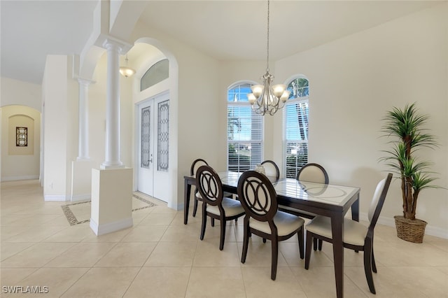 tiled dining space with an inviting chandelier, french doors, and ornate columns