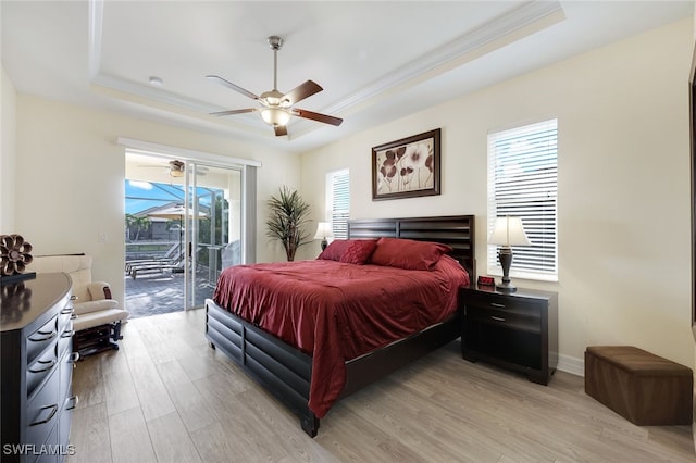 bedroom featuring ceiling fan, access to exterior, a raised ceiling, and light hardwood / wood-style floors