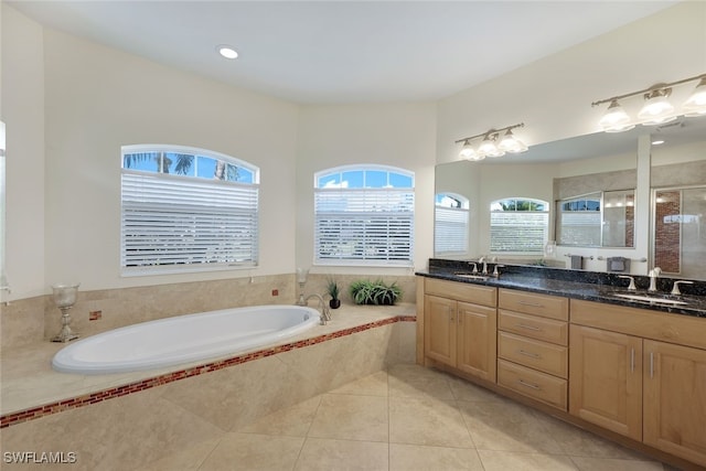 bathroom with tile patterned flooring, vanity, and tiled bath