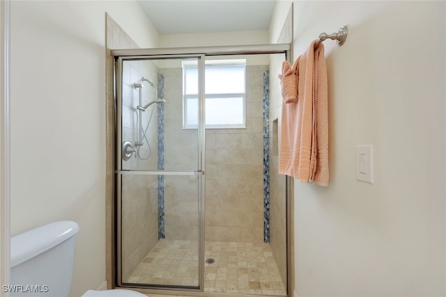 bathroom with a shower with door and toilet