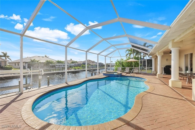 view of swimming pool with an in ground hot tub, ceiling fan, glass enclosure, a water view, and a patio area