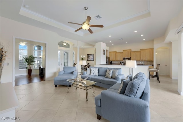 living room with light tile patterned flooring, ceiling fan, and a raised ceiling