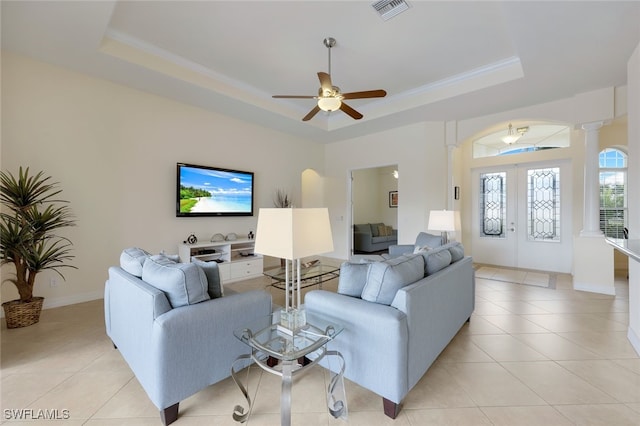 living room with a raised ceiling, ornate columns, ceiling fan, and french doors