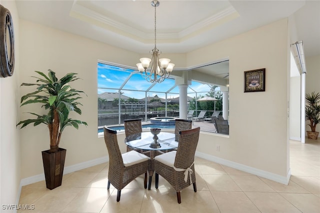 tiled dining area with a notable chandelier, ornamental molding, a raised ceiling, and a healthy amount of sunlight