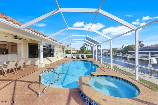 view of pool with a patio, an in ground hot tub, a lanai, ceiling fan, and a water view