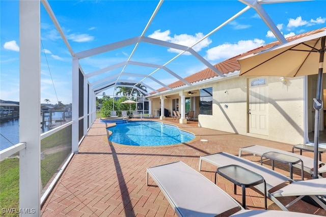 view of swimming pool with a water view, a patio, ceiling fan, and glass enclosure