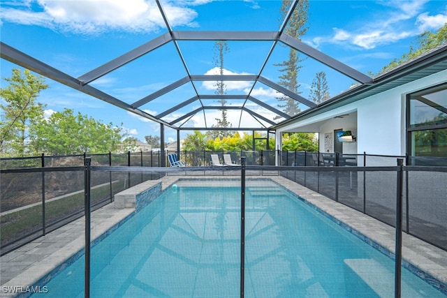 view of swimming pool featuring a patio, ceiling fan, and glass enclosure