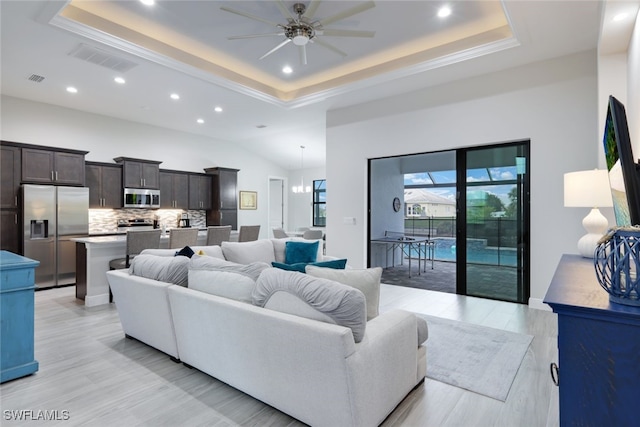 living room featuring light wood-type flooring, ceiling fan, and a raised ceiling