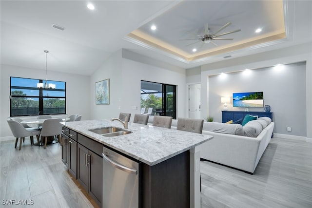 kitchen with sink, stainless steel dishwasher, a center island with sink, and a raised ceiling