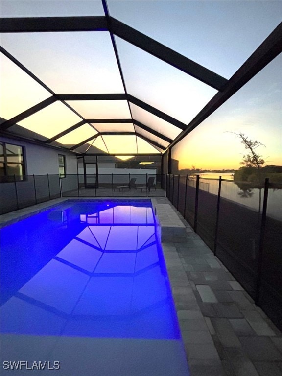 pool at dusk with a lanai and a water view