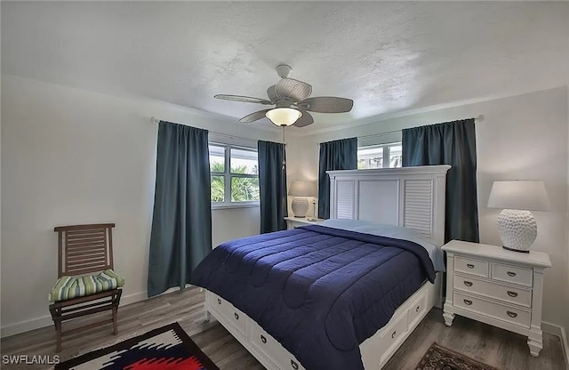 bedroom with ceiling fan, dark wood-type flooring, and multiple windows