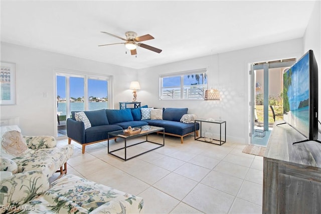 tiled living room featuring ceiling fan and a water view