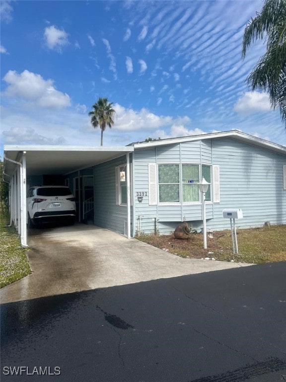 manufactured / mobile home featuring concrete driveway and a carport